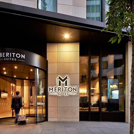Meriton Suites Sussex Street, Σίδνεϊ Εξωτερικό φωτογραφία The photo shows the entrance of a hotel or suite establishment named "Meriton Suites." The entrance features a revolving door and a large, illuminated sign with the name "MERITON SUITES." The facade is modern and sleek, with a combination of glass an