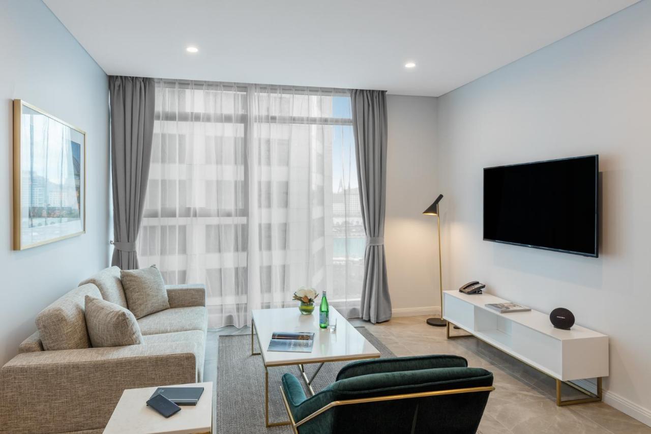 Meriton Suites Sussex Street, Σίδνεϊ Εξωτερικό φωτογραφία The photo shows a modern living room space with a light, airy ambiance. It features a comfortable beige sofa with decorative cushions, a sleek coffee table placed in front, and a dark green armchair. There is a large window covered with sheer curtain